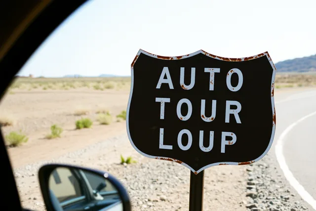 Weathered vintage highway sign on a post beside a paved auto tour loop. Seeing vintage highway signs while keeping travel accessible and short