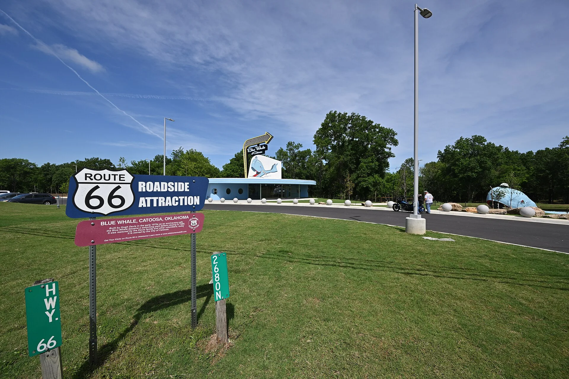 The Route 66 Roadside Attraction sign, with the brand-new Blue Whale of Catoosa visitor center behind it, and the Blue Whale to the right. 2600 OK-66, Catoosa, Oklahoma 74015. Roadside attractions booking: what to ask before you pay